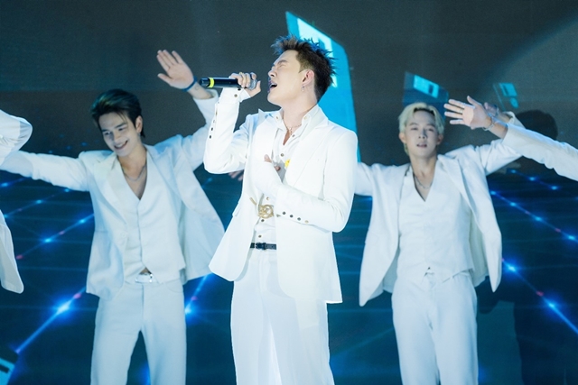 A group of men in white outfits singing into a microphoneAI-generated content may be incorrect.
