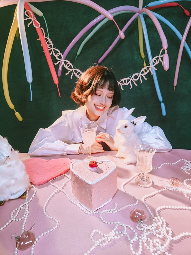A person sitting at a table with a cake and a bunnyAI-generated content may be incorrect.